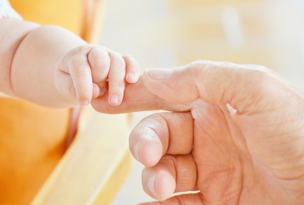 Holding hands with a baby representing sense of touch