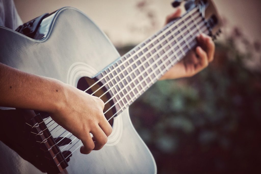 Person playing a guitar representing sense of sounds